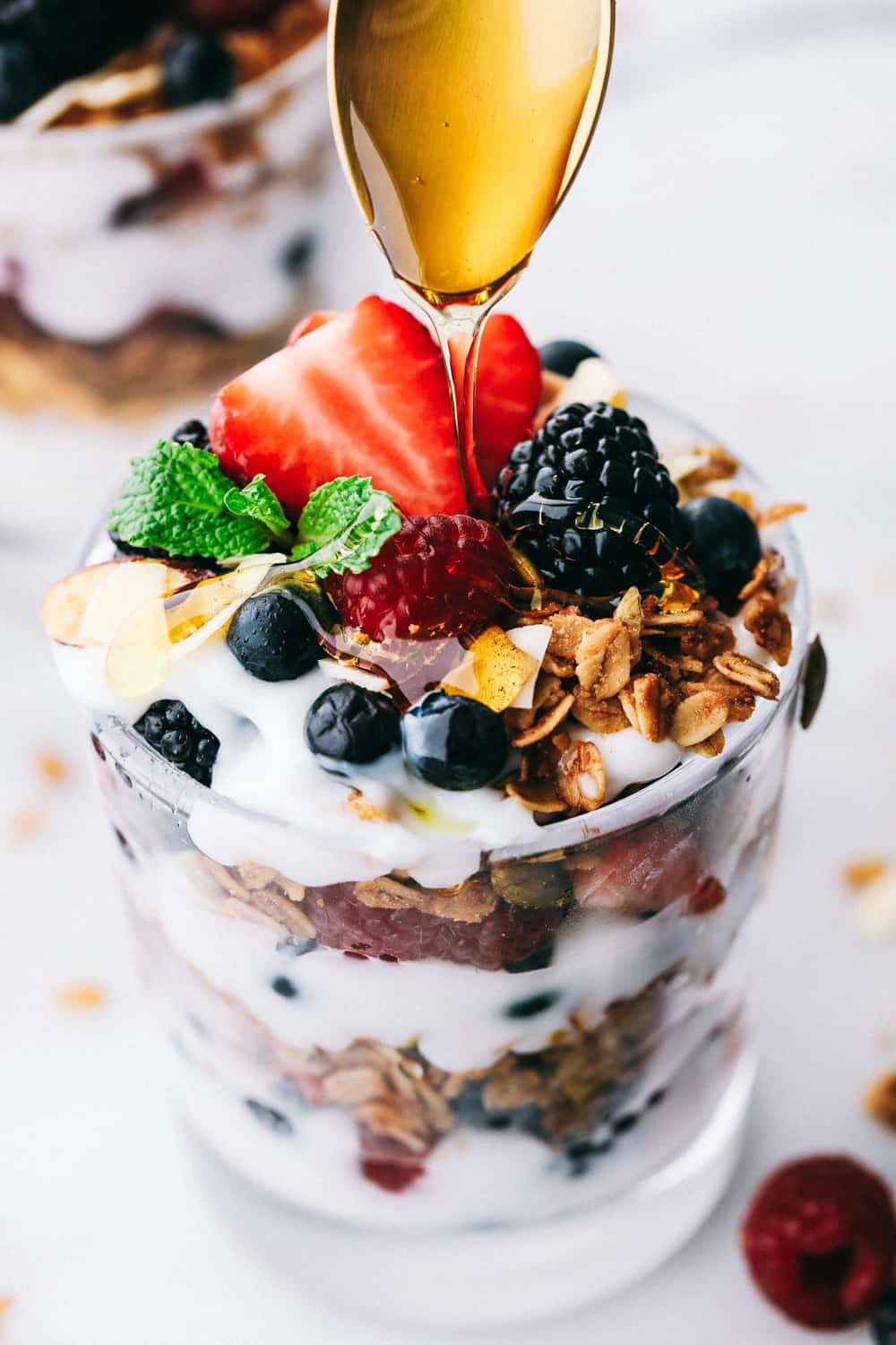 parfait honey, yogurt and berry parfait with granola in glass dish